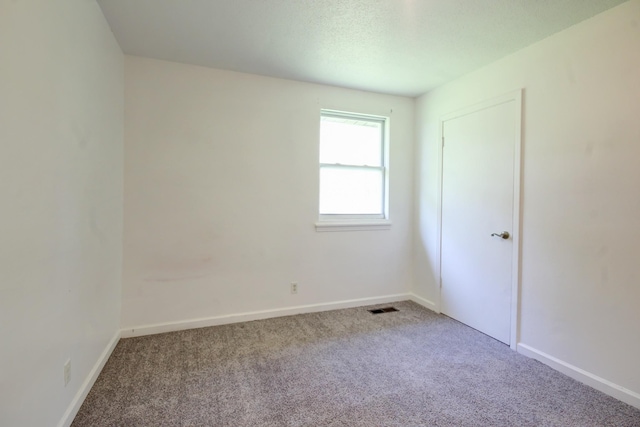 carpeted spare room featuring baseboards and visible vents