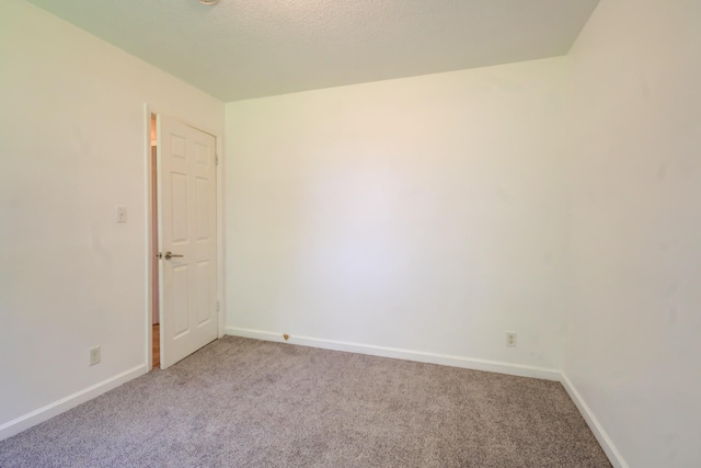 carpeted spare room featuring baseboards