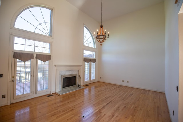 2132 Neelys Bend Rd, Madison, TN 37115 - unfurnished living room featuring a chandelier, light wood-type flooring, a high end fireplace, a high ceiling, and baseboards