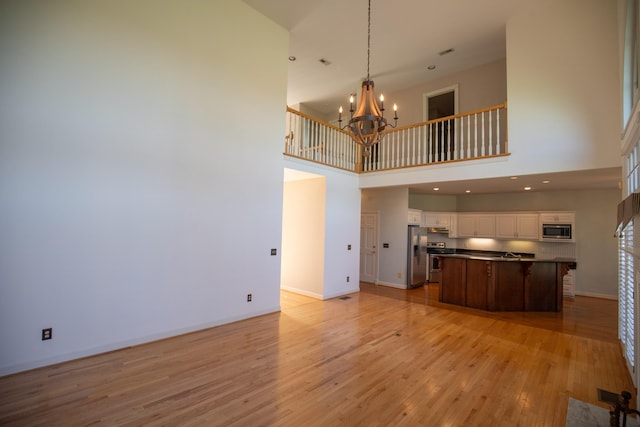 2132 Neelys Bend Rd, Madison, TN 37115 - unfurnished living room featuring a chandelier, a high ceiling, light wood finished floors, and baseboards