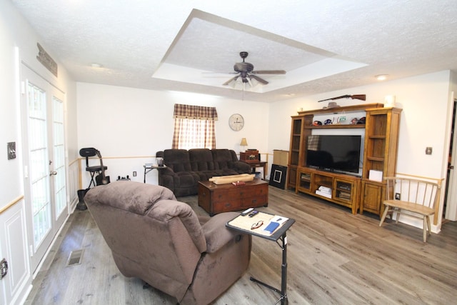 320 Benson Rd, Reagan, TN 38368 - living room with light wood finished floors, a tray ceiling, a textured ceiling, and a healthy amount of sunlight