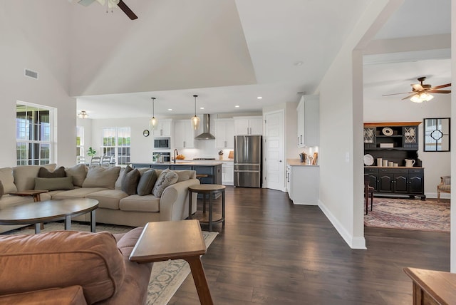 living area with dark wood-type flooring, visible vents, baseboards, and ceiling fan