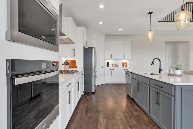 kitchen featuring white cabinetry, light countertops, a sink, stainless steel appliances, and gray cabinetry