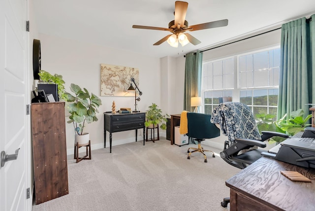 office area featuring light carpet, baseboards, and a ceiling fan