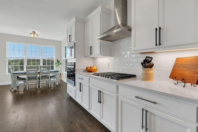 kitchen with wall chimney exhaust hood, white cabinets, stainless steel gas cooktop, decorative backsplash, and dark wood-style floors