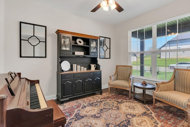 living area with baseboards, wood finished floors, and ceiling fan