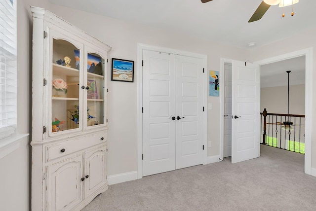 unfurnished bedroom with a closet, baseboards, ceiling fan, and light colored carpet