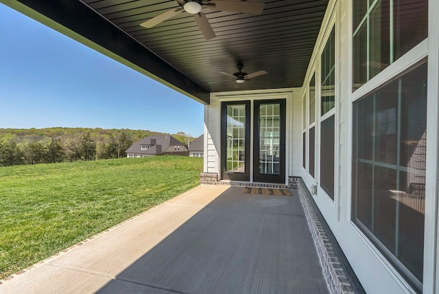 view of patio with a view of trees and ceiling fan