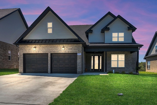 view of front of home with a yard, an attached garage, concrete driveway, brick siding, and a standing seam roof