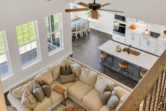 living area with dark wood finished floors, baseboards, a ceiling fan, and visible vents