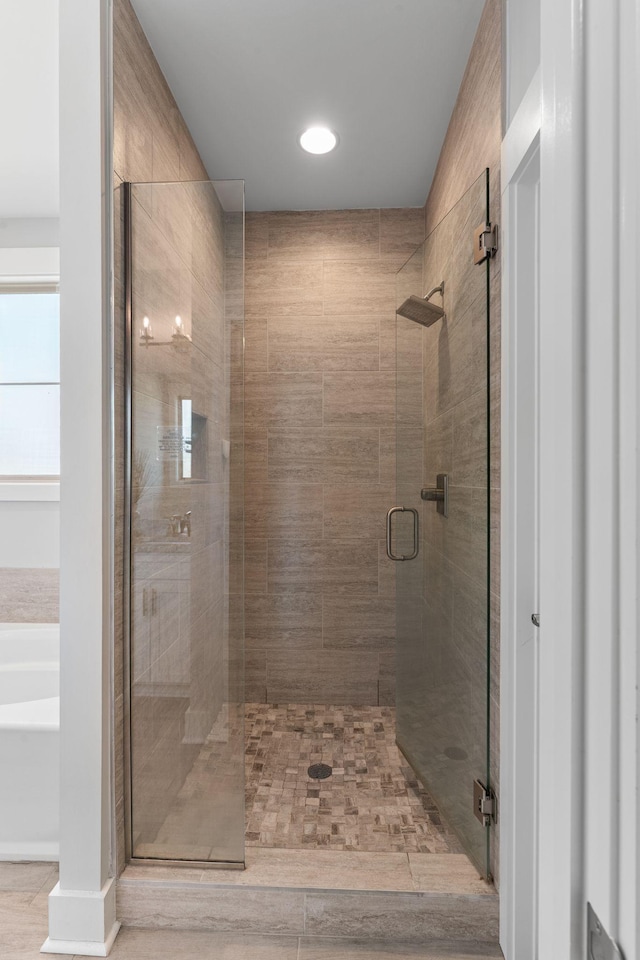 full bathroom with a shower stall and a bath