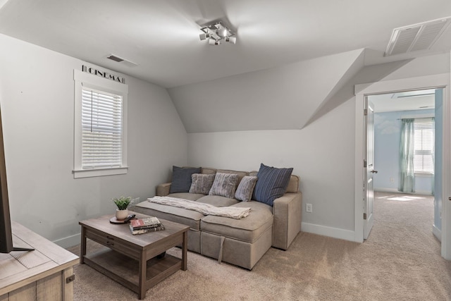 living room featuring light colored carpet, baseboards, lofted ceiling, and visible vents