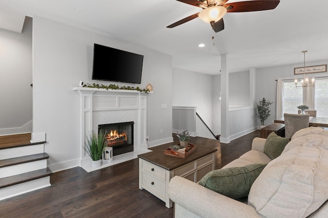 living area featuring dark wood-style flooring, baseboards, recessed lighting, and ceiling fan with notable chandelier