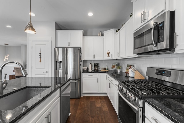 kitchen featuring hanging light fixtures, a sink, appliances with stainless steel finishes, dark wood-type flooring, and decorative backsplash