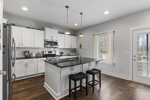 kitchen featuring stainless steel appliances, dark wood-style floors, a sink, and backsplash