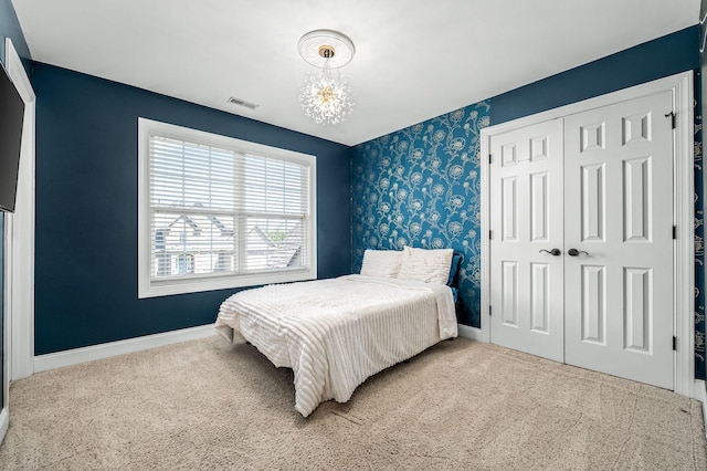 carpeted bedroom with a closet, visible vents, a chandelier, wallpapered walls, and baseboards