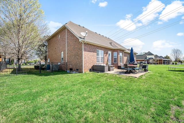 back of house featuring crawl space, a lawn, fence, a patio, and brick siding