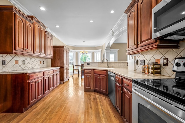 kitchen with arched walkways, a sink, ornamental molding, and appliances with stainless steel finishes