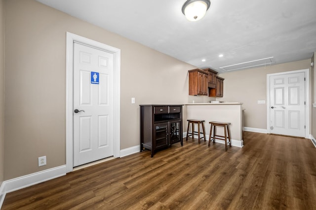kitchen with dark wood-style flooring, baseboards, a peninsula, and a kitchen bar
