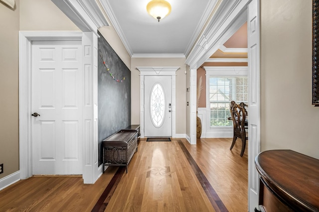 foyer with decorative columns, baseboards, ornamental molding, and wood finished floors