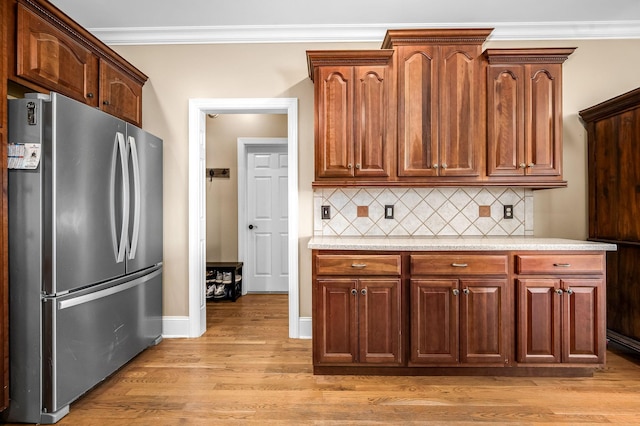 kitchen featuring light wood-style floors, freestanding refrigerator, light countertops, and ornamental molding