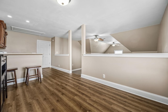 interior space featuring ceiling fan, vaulted ceiling, attic access, dark wood-style flooring, and baseboards