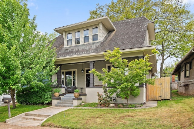 view of front of home featuring a gate, a front lawn, a porch, fence, and a shingled roof