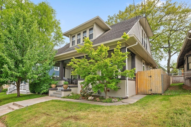 view of front of home featuring fence, a front yard, a gate, and a shingled roof