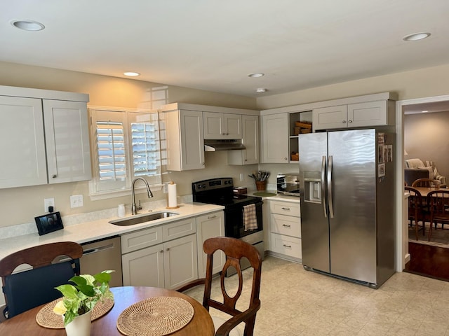 kitchen featuring recessed lighting, appliances with stainless steel finishes, under cabinet range hood, light countertops, and a sink