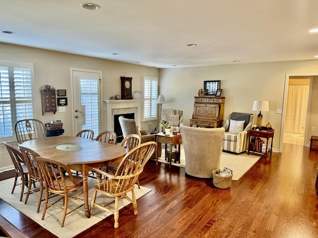 dining space with recessed lighting, a premium fireplace, baseboards, and wood finished floors
