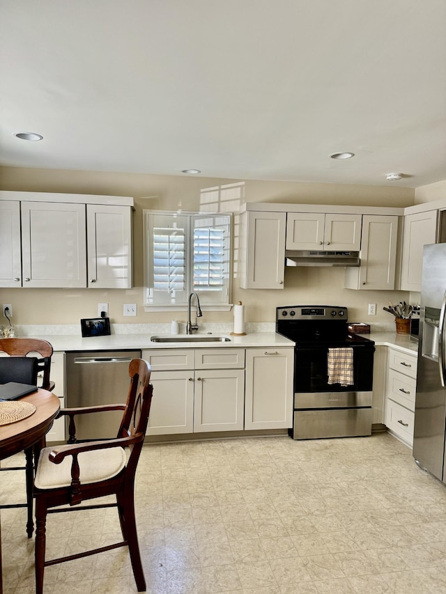 kitchen with recessed lighting, appliances with stainless steel finishes, under cabinet range hood, light countertops, and a sink