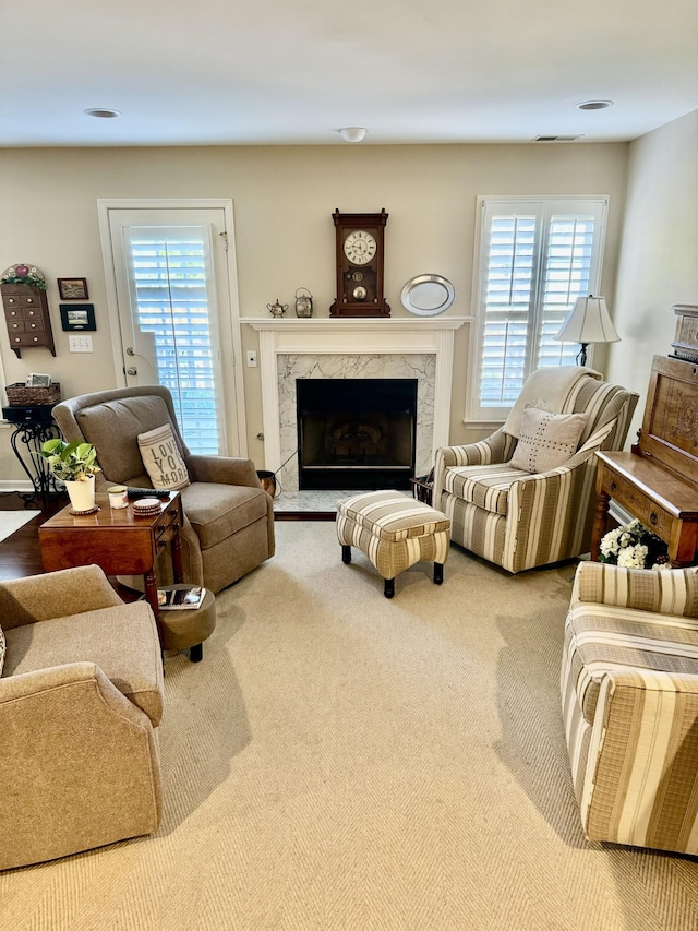 carpeted living area with a premium fireplace