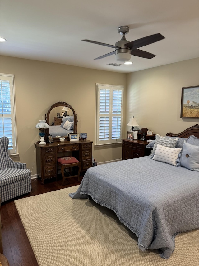 bedroom featuring visible vents, multiple windows, baseboards, and wood finished floors