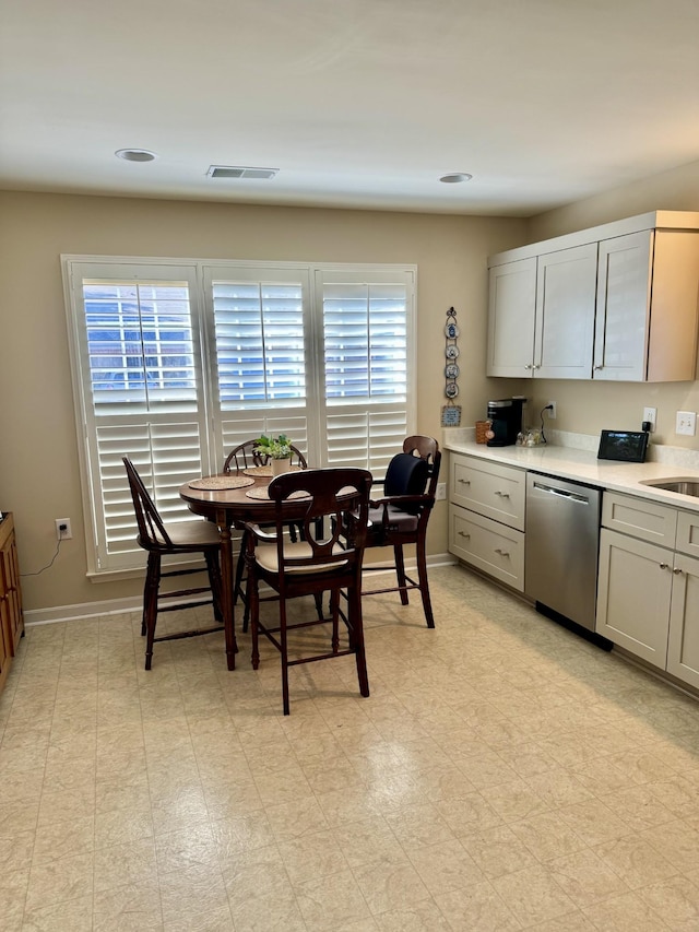 kitchen featuring baseboards, gray cabinets, light countertops, light floors, and dishwasher