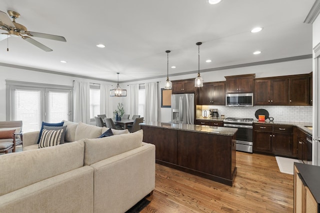 kitchen featuring open floor plan, ceiling fan, ornamental molding, dark brown cabinets, and stainless steel appliances