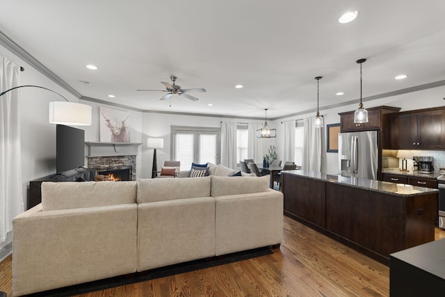 living room with recessed lighting, a fireplace, ornamental molding, and ceiling fan
