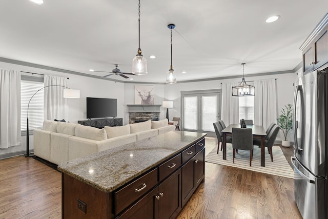 kitchen with freestanding refrigerator, a fireplace, recessed lighting, stone countertops, and decorative light fixtures
