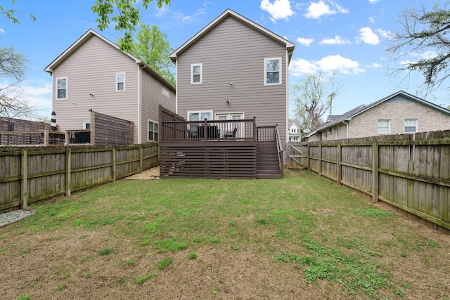 back of house featuring a deck, a fenced backyard, and a lawn