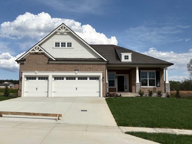 craftsman house featuring roof with shingles, a front lawn, a garage, and concrete driveway