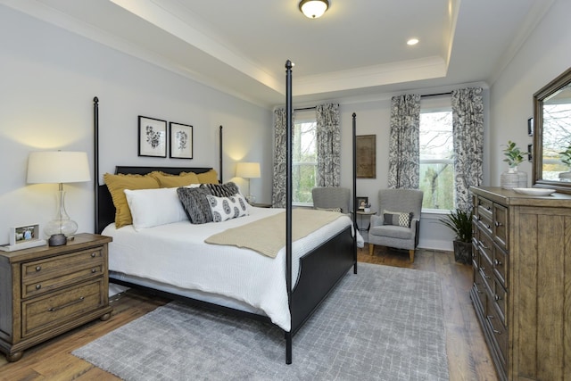bedroom featuring dark wood-type flooring, ornamental molding, and a raised ceiling