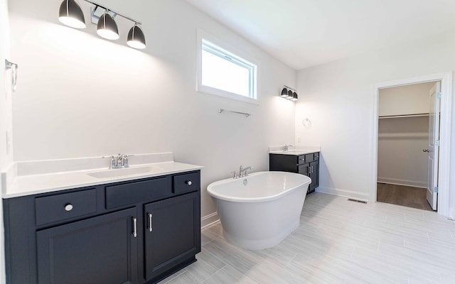 7705 Pine St, Fairview, TN 37062 - bathroom featuring two vanities, a soaking tub, baseboards, and a spacious closet