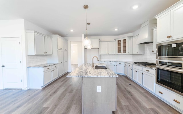 7705 Pine St, Fairview, TN 37062 - kitchen with appliances with stainless steel finishes, a sink, decorative backsplash, light wood-style flooring, and light stone countertops