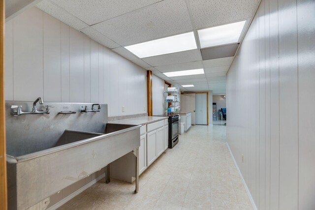 kitchen with light countertops, a paneled ceiling, white cabinetry, and black electric range oven