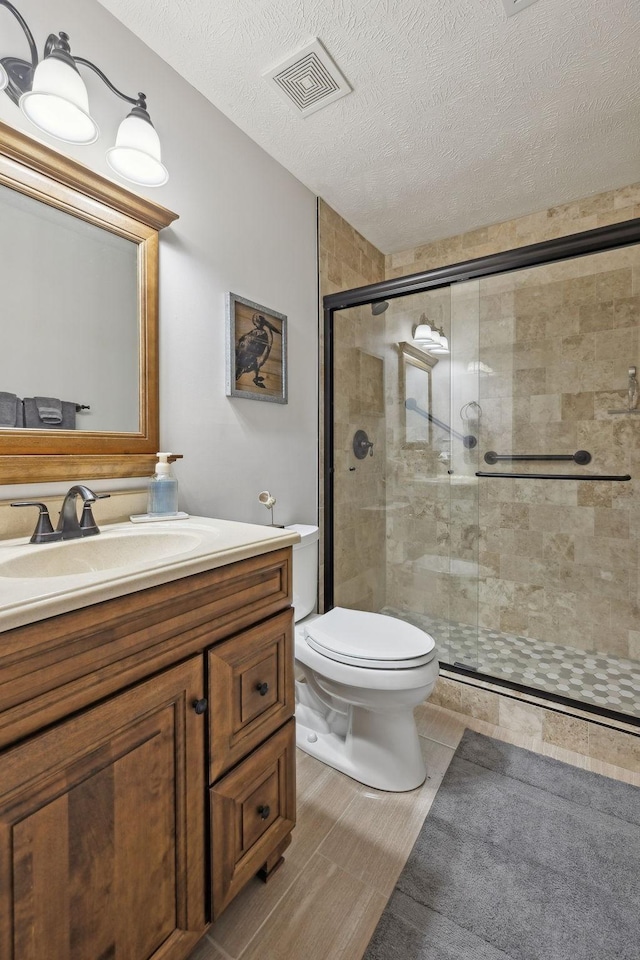 1006 Harmony Ln, Hendersonville, TN 37075 - bathroom featuring vanity, a textured ceiling, toilet, a shower stall, and visible vents