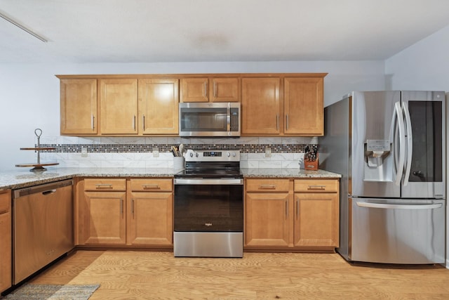 1006 Harmony Ln, Hendersonville, TN 37075 - kitchen featuring tasteful backsplash, light wood-type flooring, light stone countertops, brown cabinets, and appliances with stainless steel finishes