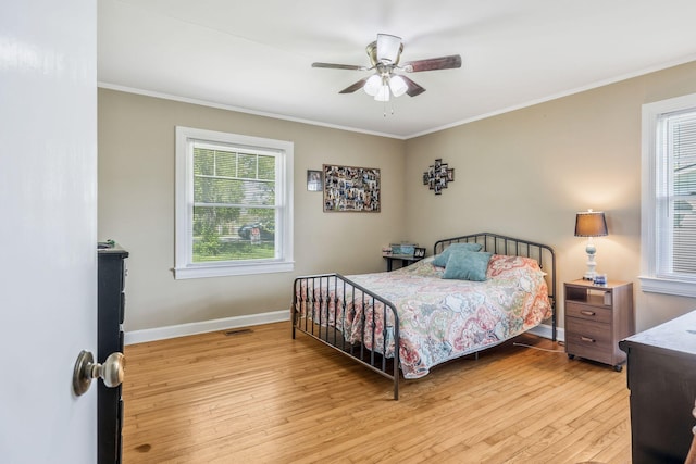 bedroom featuring ceiling fan, baseboards, crown molding, and wood finished floors