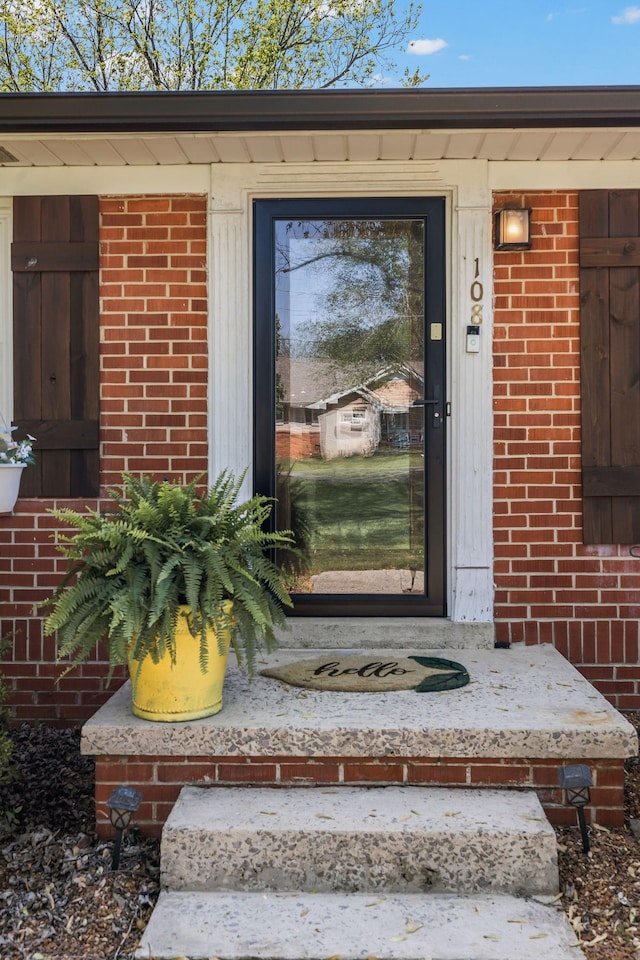 entrance to property featuring brick siding