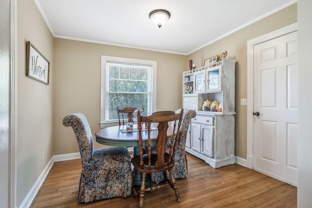 dining space featuring baseboards, light wood-type flooring, and ornamental molding