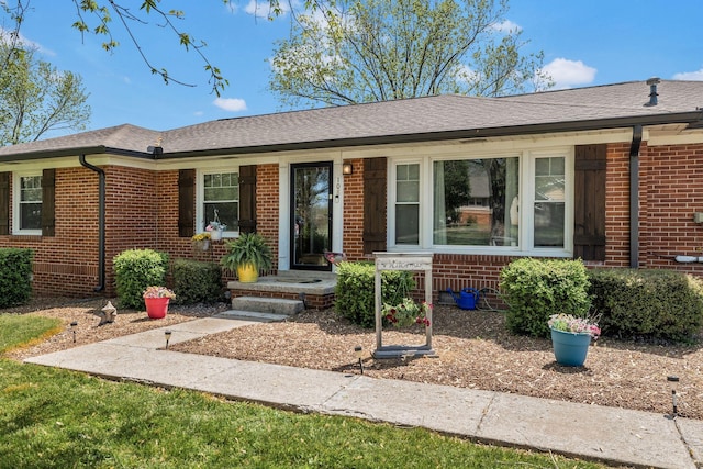 ranch-style house featuring brick siding and a shingled roof