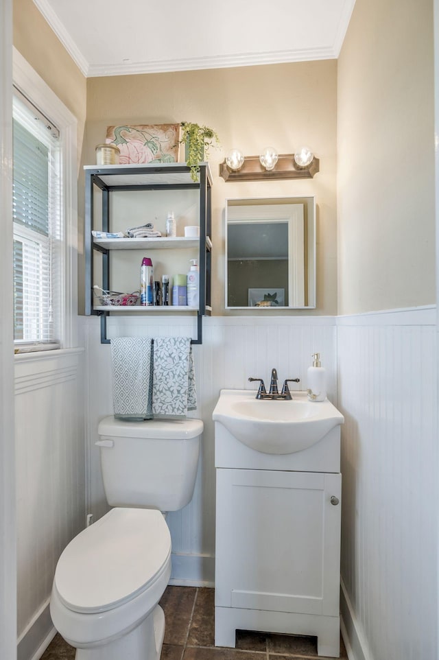 bathroom with ornamental molding, toilet, vanity, and wainscoting